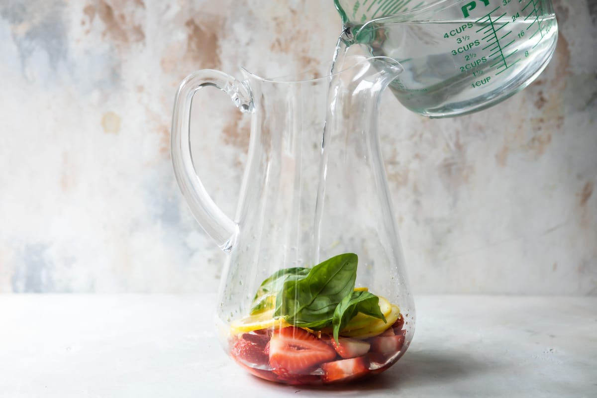 Making water infused with strawberry, lemon, and fresh basil.