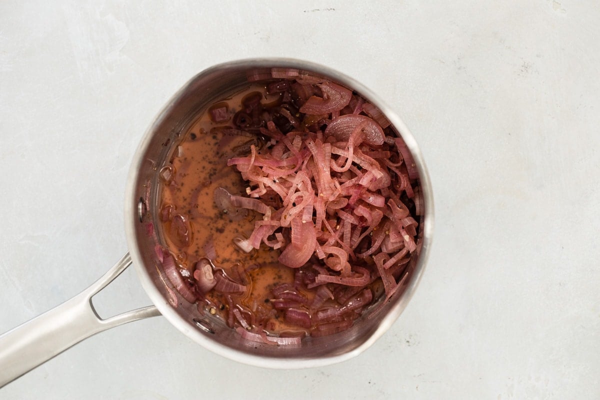 Pickled shallots in a silver saucepan.