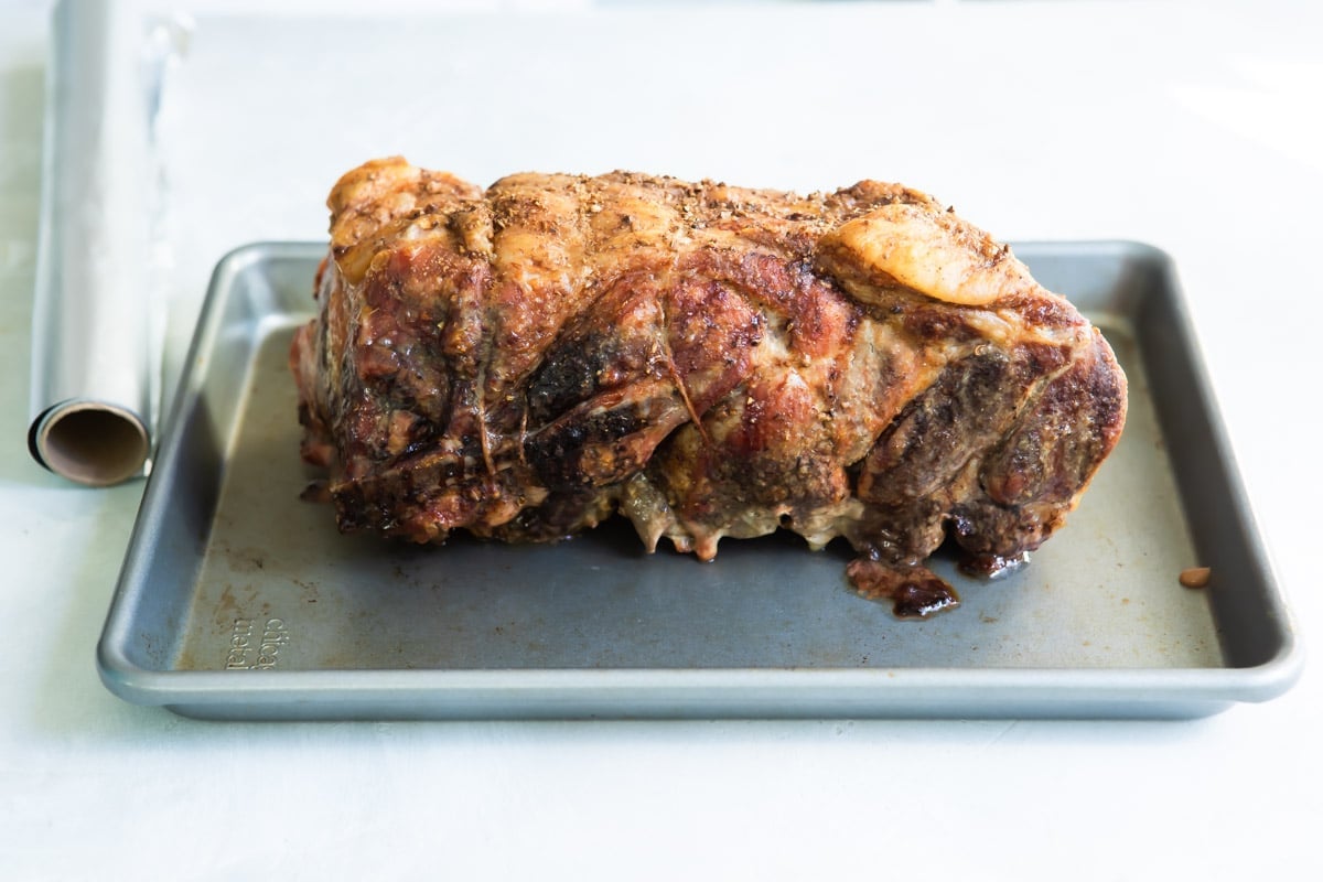A cooked pork roast on a baking sheet.