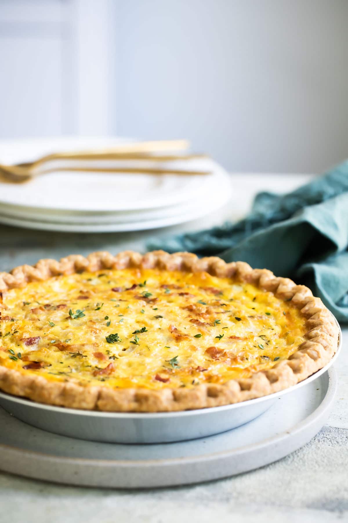 A quiche Lorraine in a pie pan on top of a round serving plate.