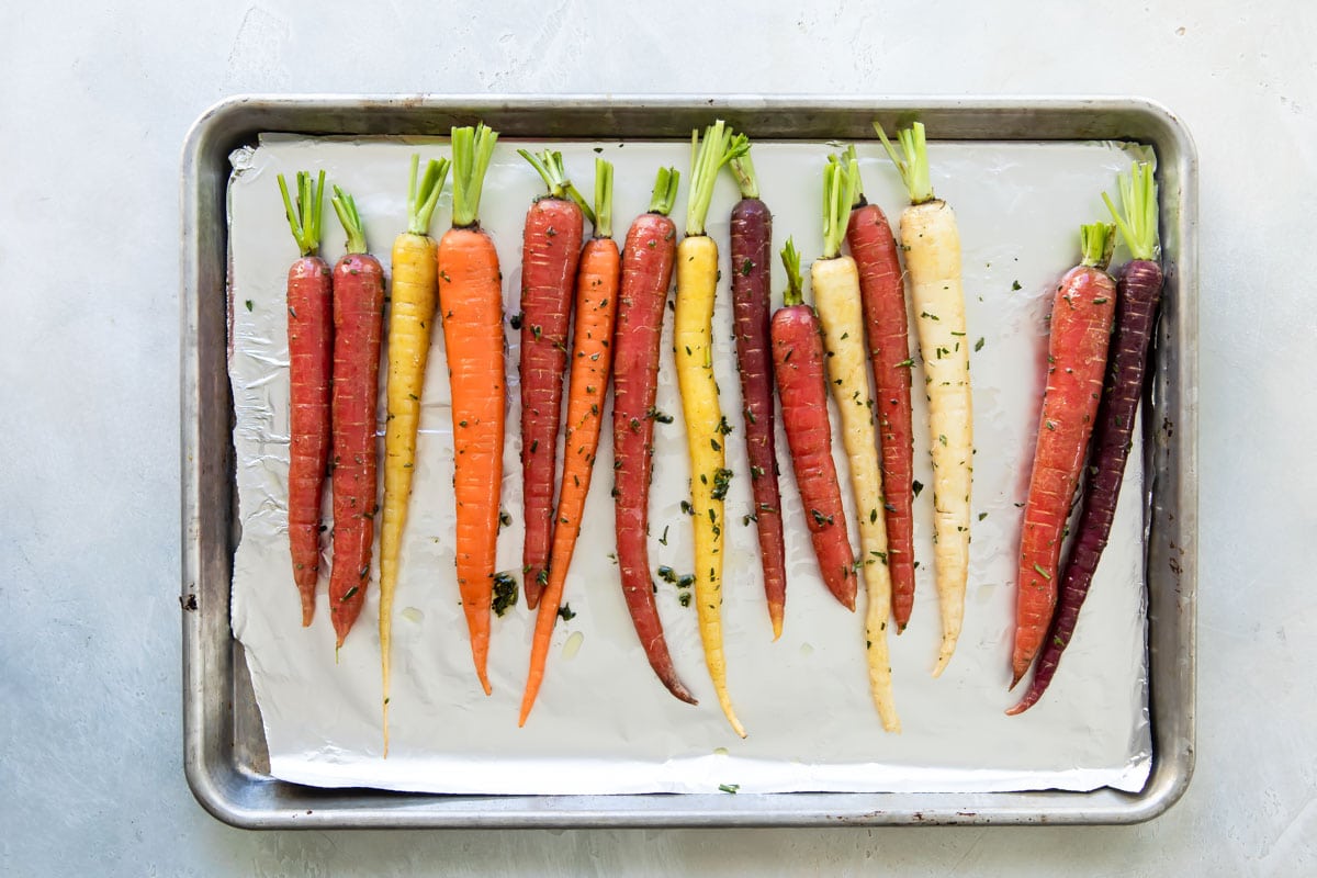 Roasted carrots on a parchment paper lined baking sheet before being roasted.