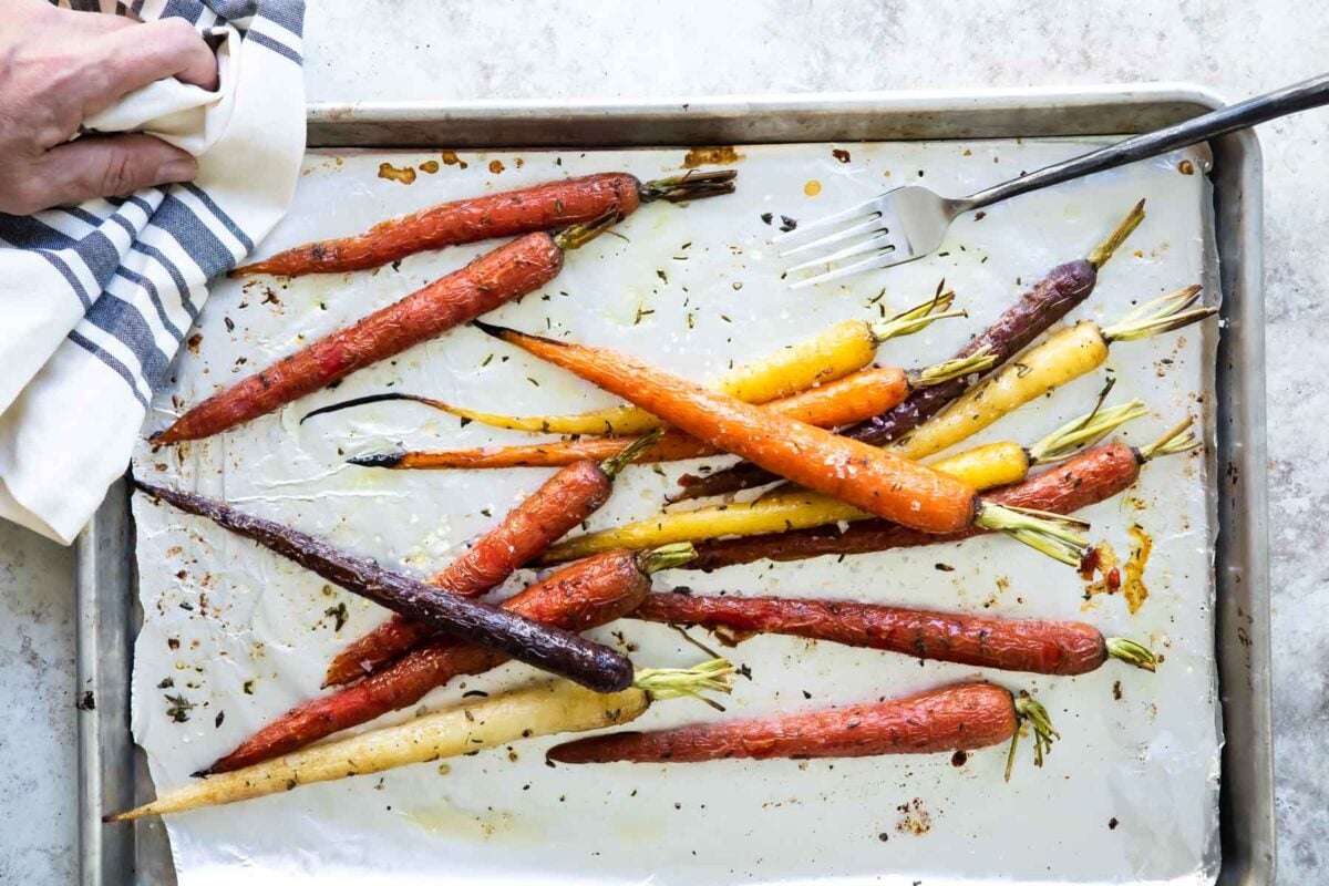 Roasted carrots on a parchment paper lined baking sheet.