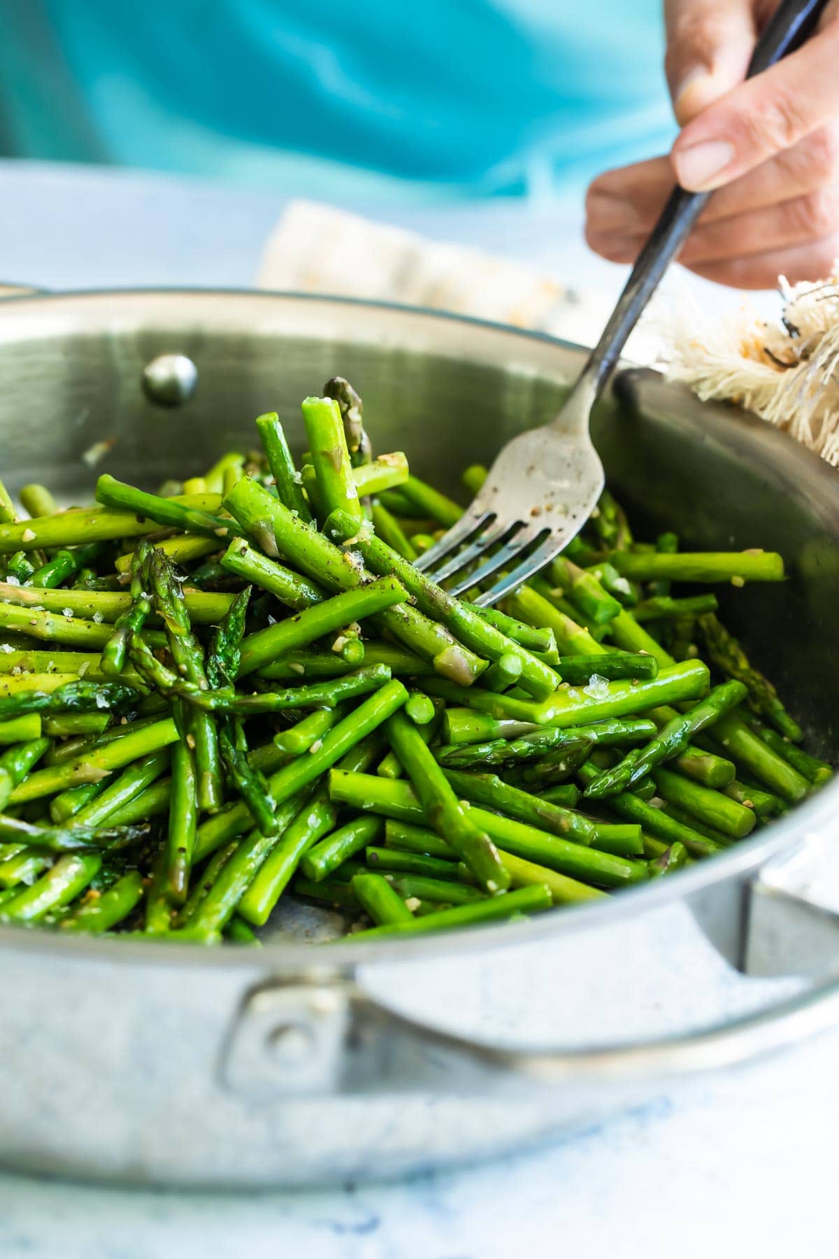 A silver skillet filled with sauteed asparagus.