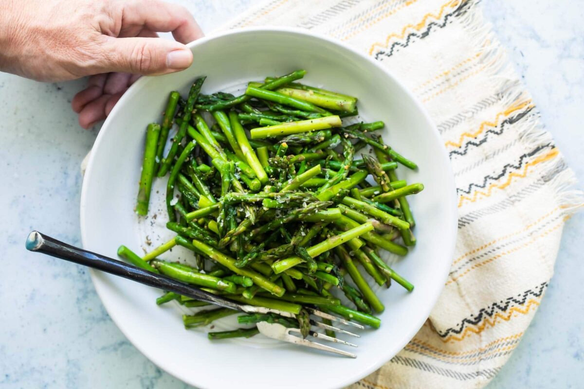 A white bowl filled with sauteed asparagus.