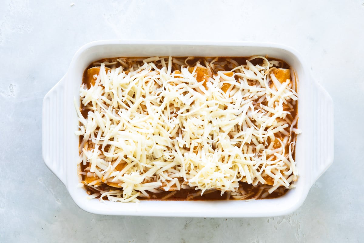 A casserole dish with chicken enchiladas before being baked.