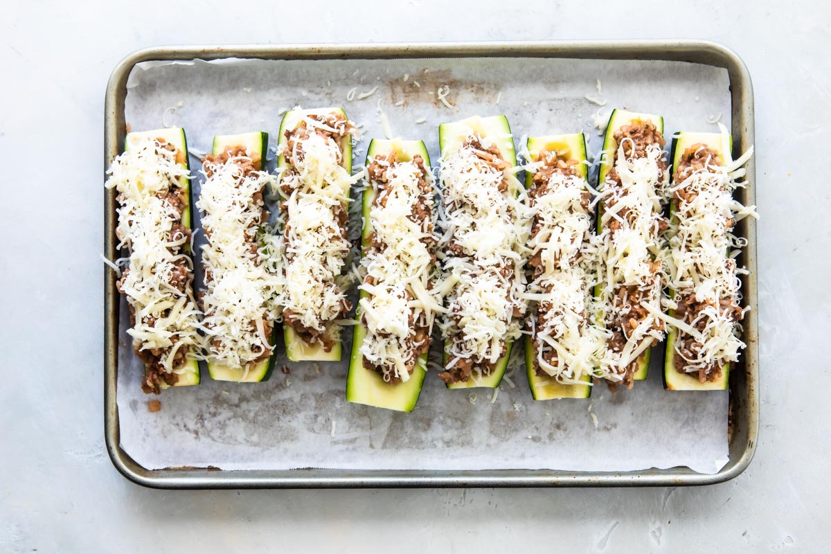 Stuffed zucchini on a baking sheet before being baked.
