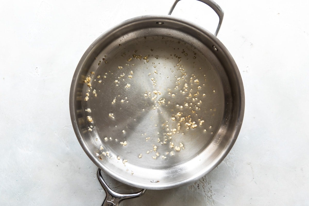 Garlic and oil in a silver skillet.