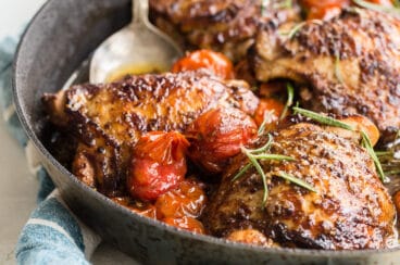Balsamic chicken and tomatoes in a black dish.