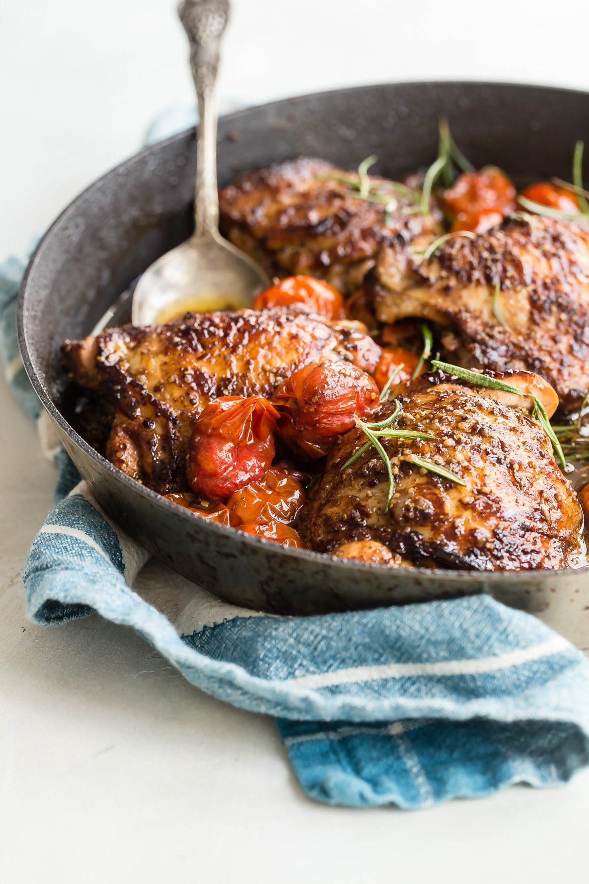 Cooked balsamic chicken and tomatoes in a black skillet.