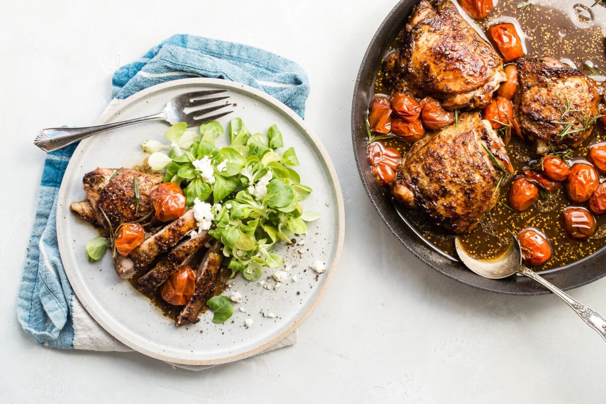 Balsamic chicken and tomatoes and a salad on a white plate.
