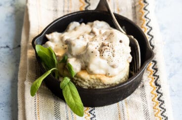 Biscuits and gravy in a small black skillet.