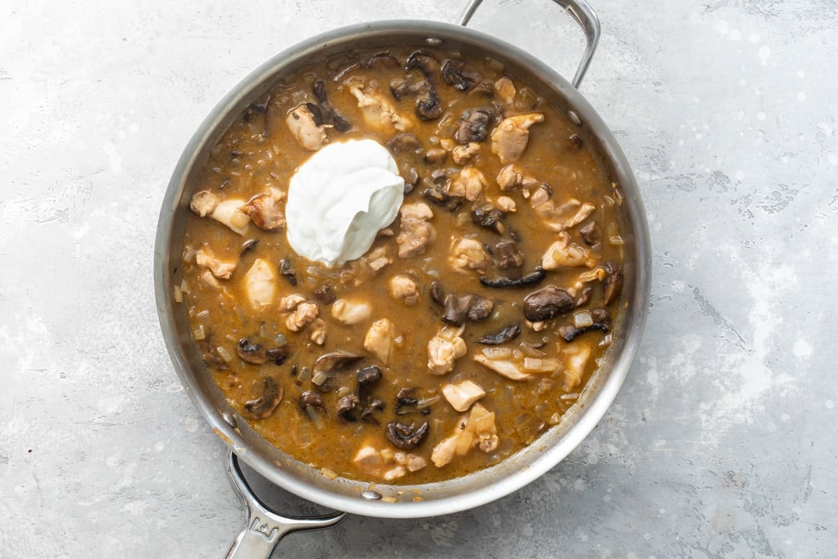 Chicken and mushroom stroganoff sauce cooking in a skillet.