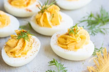Deviled eggs on a round wooden platter.