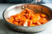 Glazed carrots in a silver skillet.