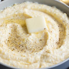A bowl of grits with a pat of butter in the middle.