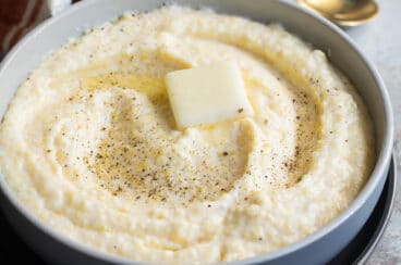 A bowl of grits with a pat of butter in the middle.