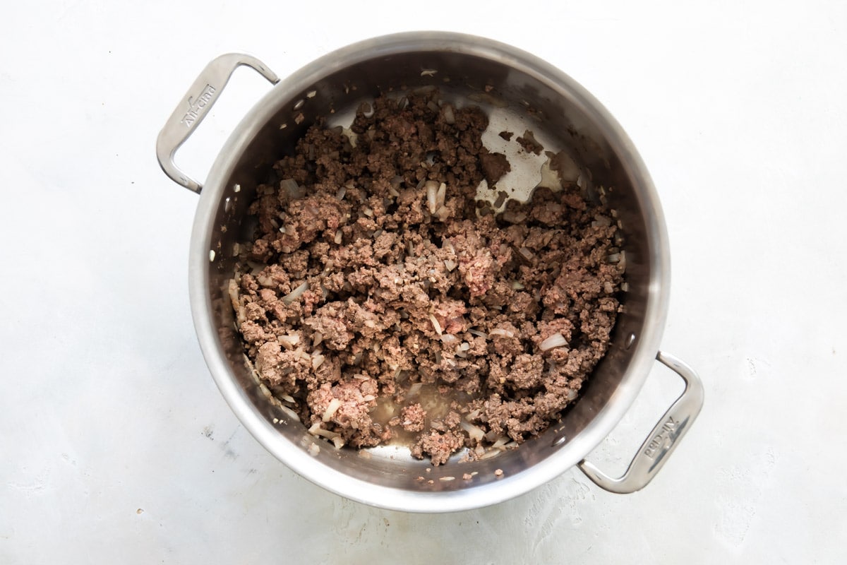 Ground beef and onion cooked in a saucepan.