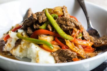 A bowl of Midwest Pepper Steak over mashed potatoes.