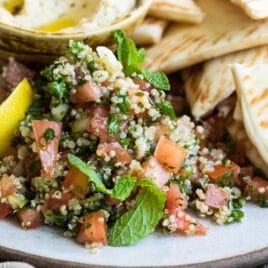 Quinoa tabbouleh on a gray plate surrounded by pita chips.