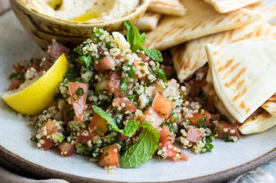 Quinoa tabbouleh on a gray plate surrounded by pita chips.