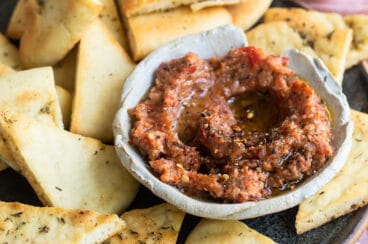 Roasted eggplant dip on a plate with triangles of bread.