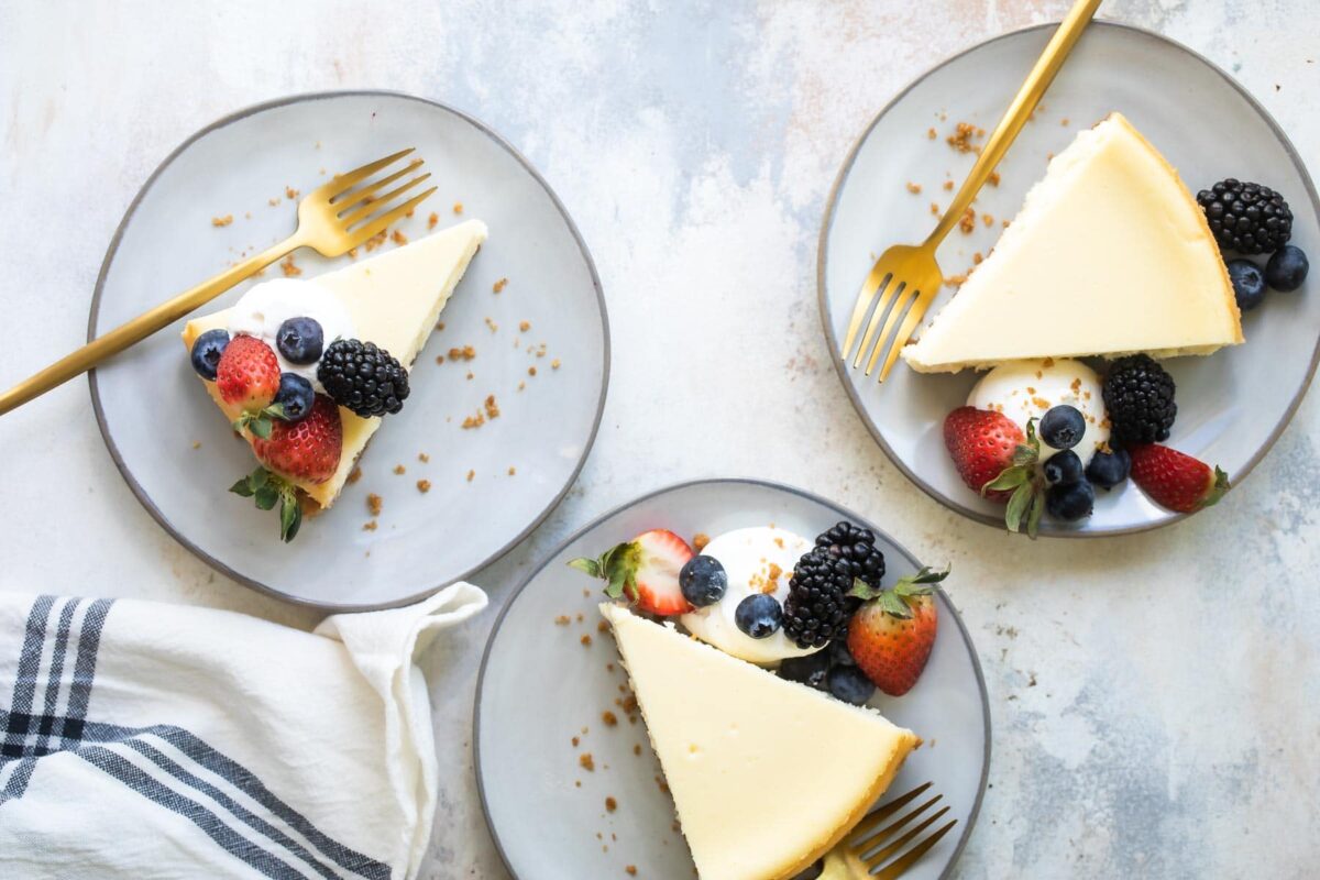 Plates of Vanilla Cheesecake with berries and whipped cream on top.