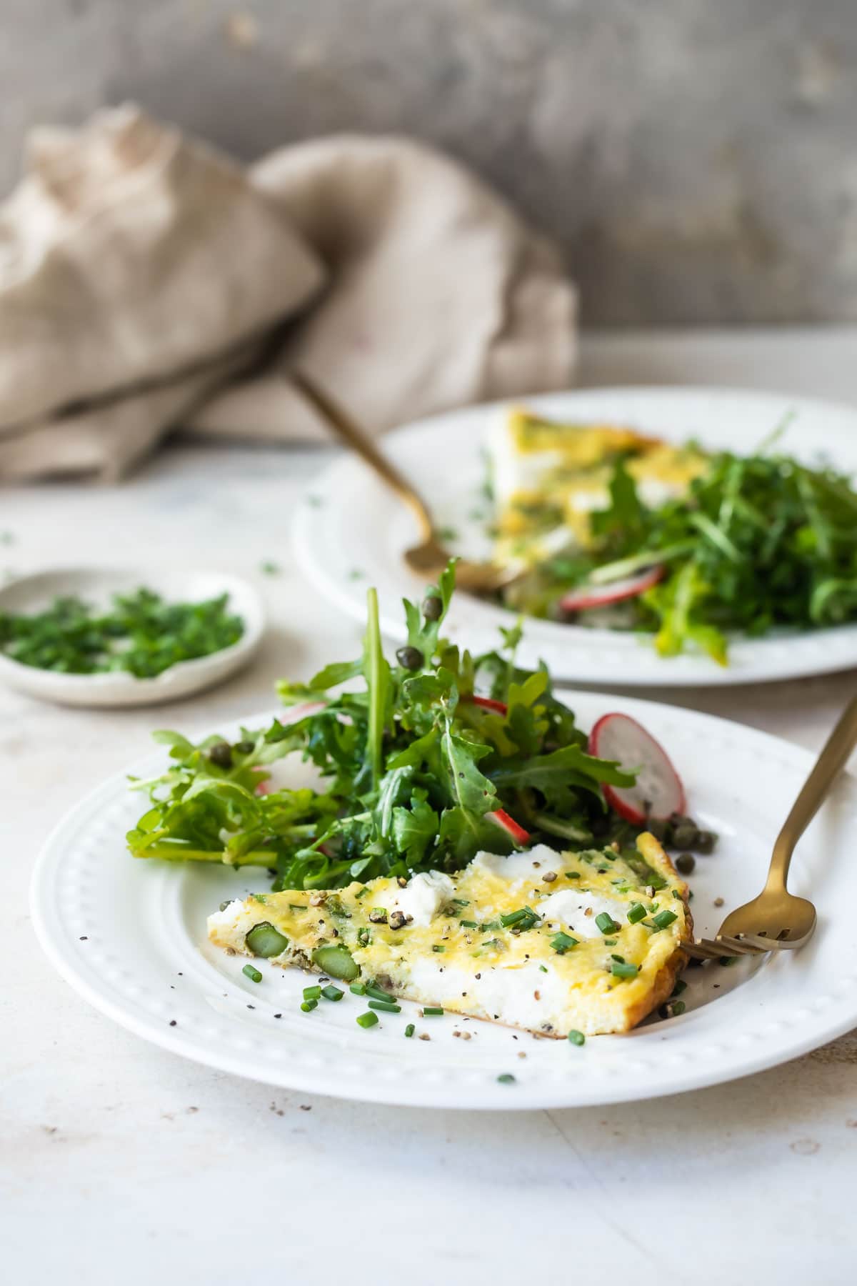 A slice of asparagus fritatta on a white plate.