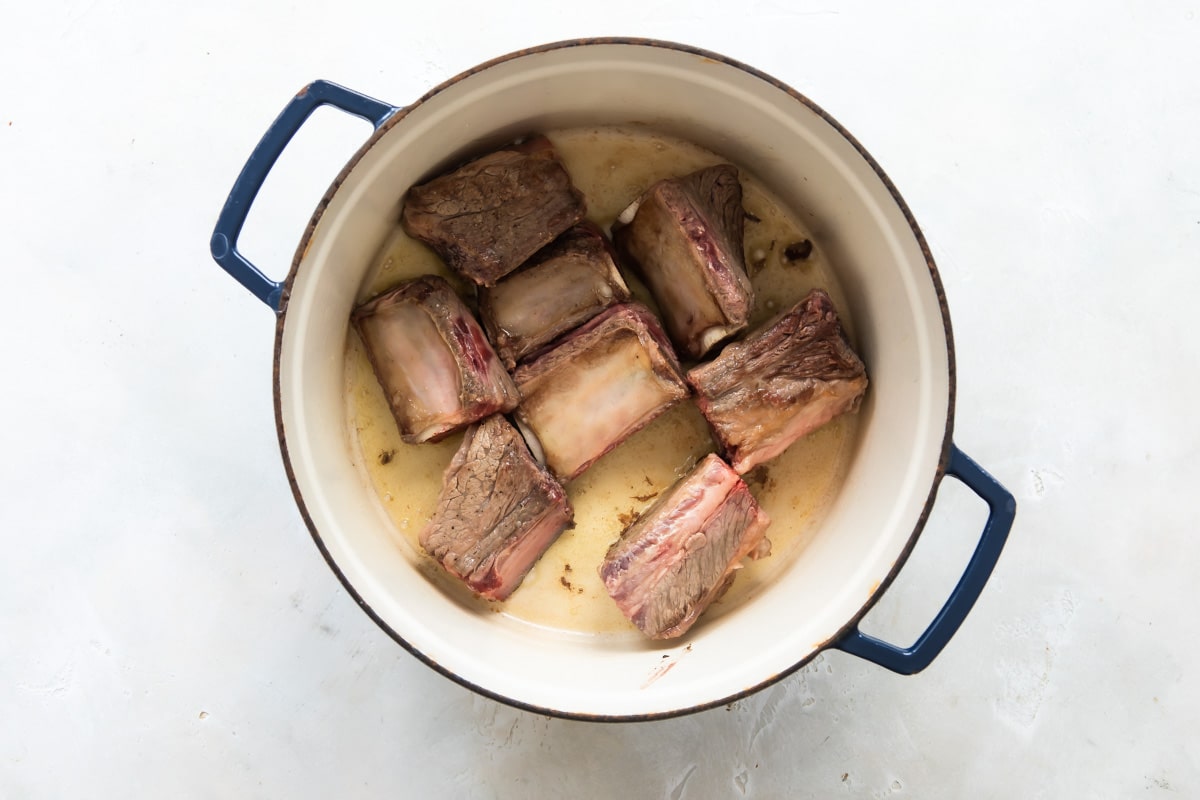 Short ribs being cooked in a Dutch oven.