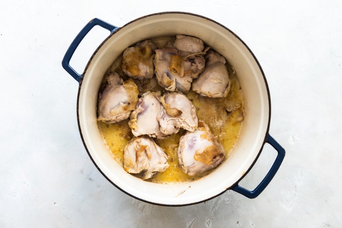 Chicken thighs being cooked in a Dutch oven.