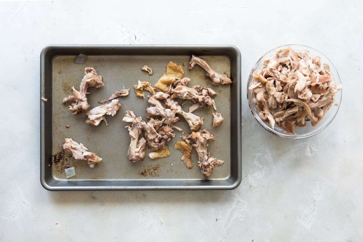 Chicken thigh remnants on a baking sheet after meat has been removed.