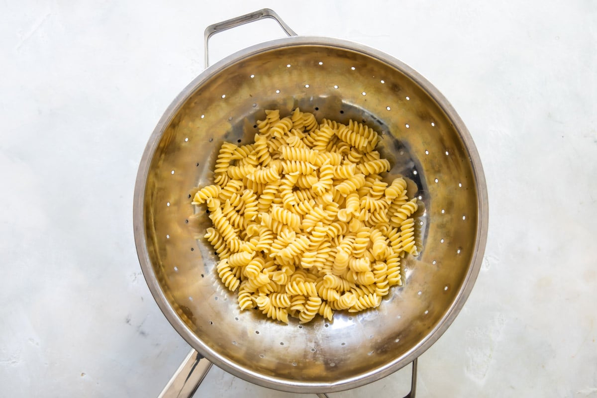Cooked rotini in a silver colander.