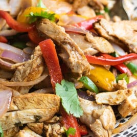 Chicken fajitas on a blue and white serving platter.