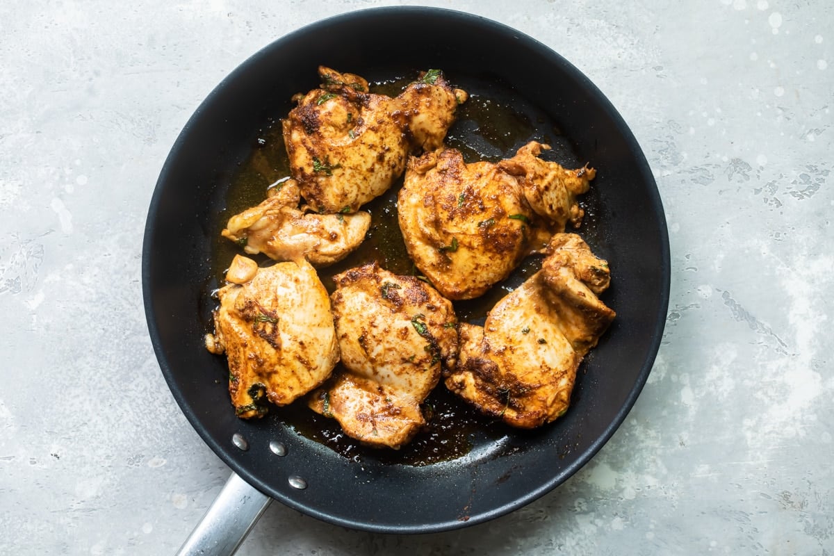 Chicken cooking on a black skillet.