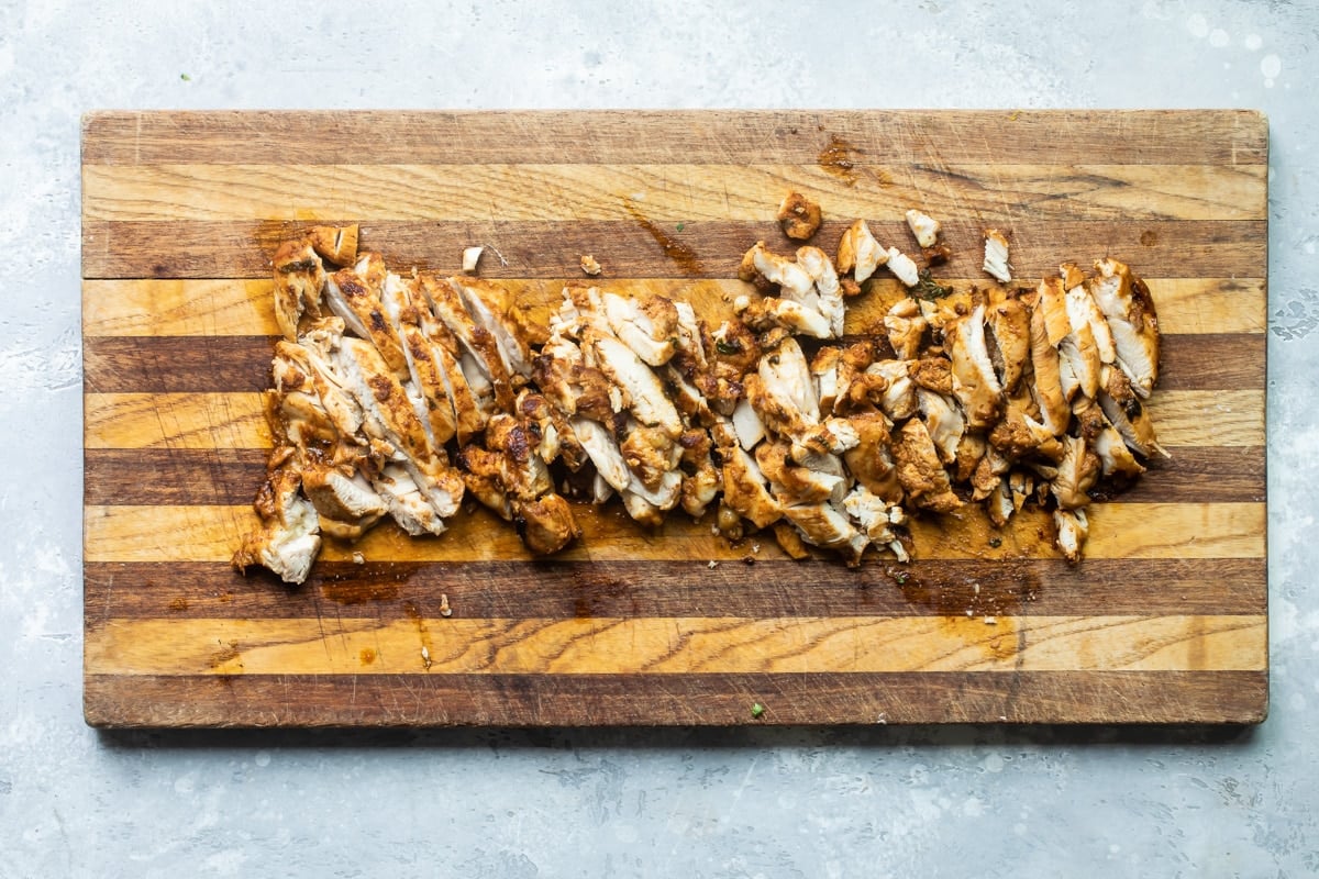 Sliced chicken on a wood cutting board.