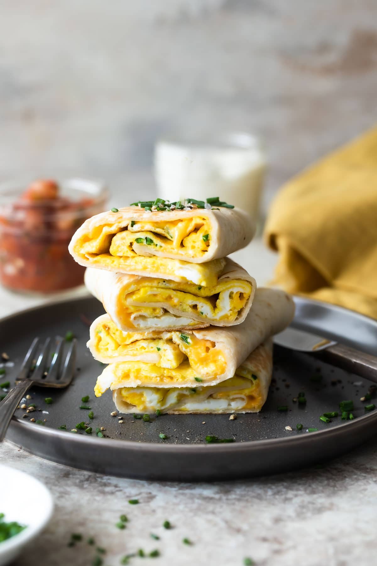 Egg burritos stacked on a gray plate.