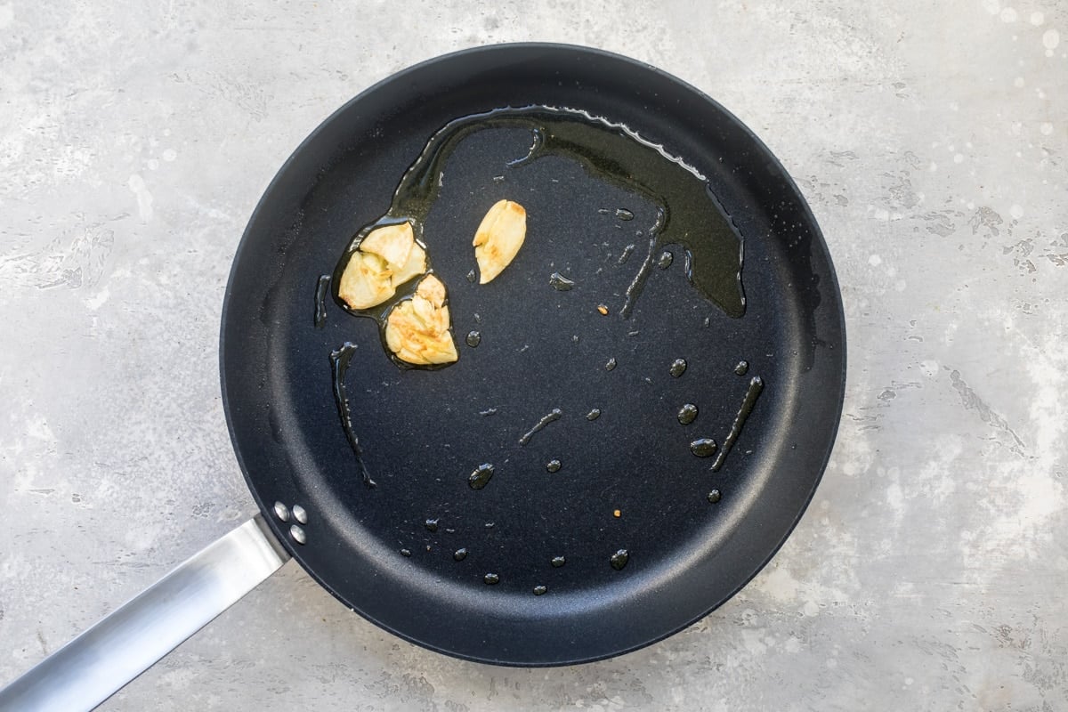 Browning sliced garlic in a skillet with oil.