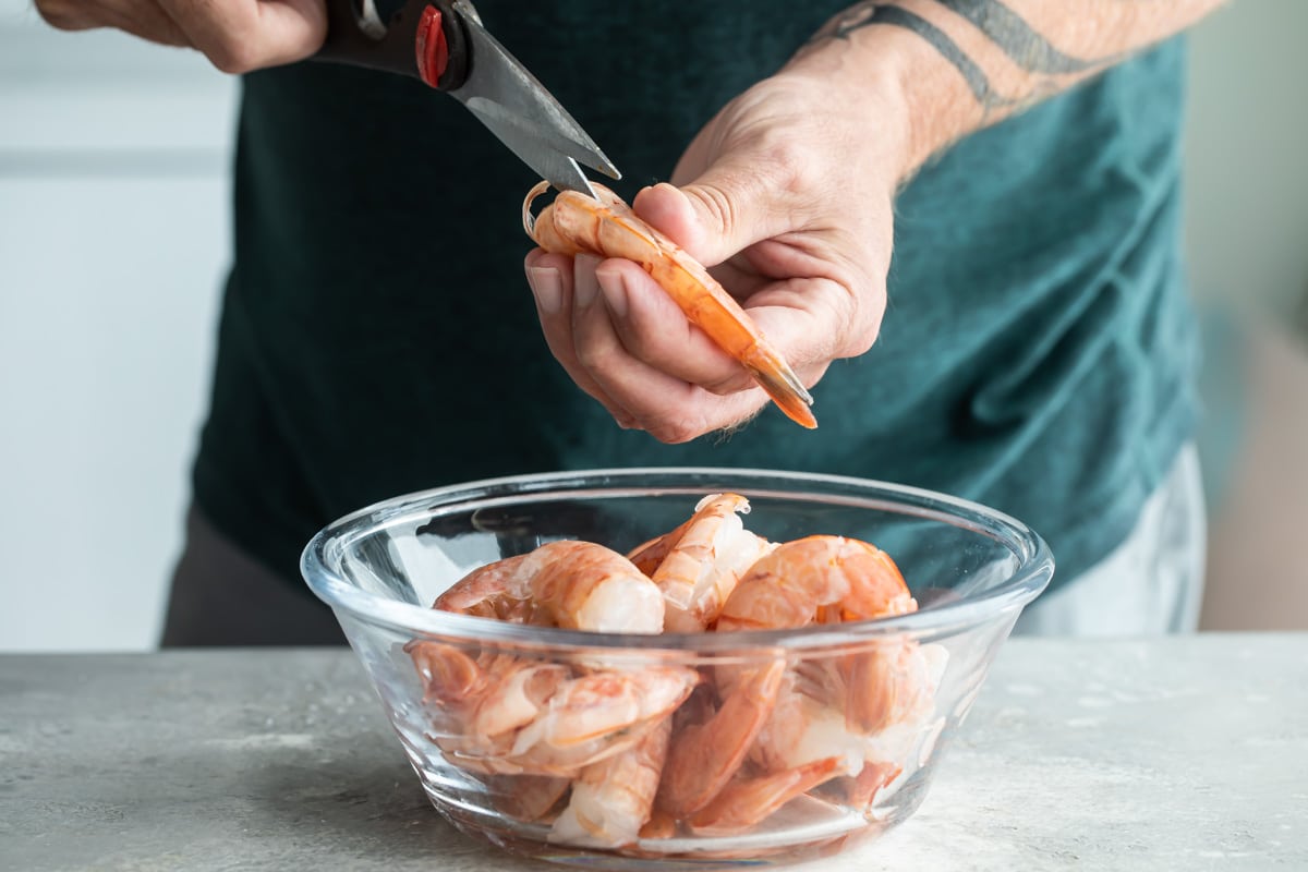 Shrimp being cut with kitchen shears.