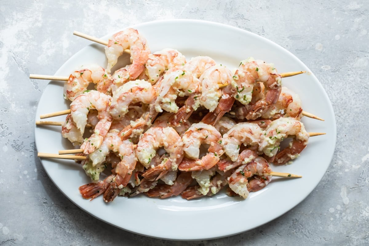 A plate of skewered shrimp for grilling.