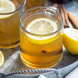 Hot toddies in clear glass mugs on a silver serving tray.