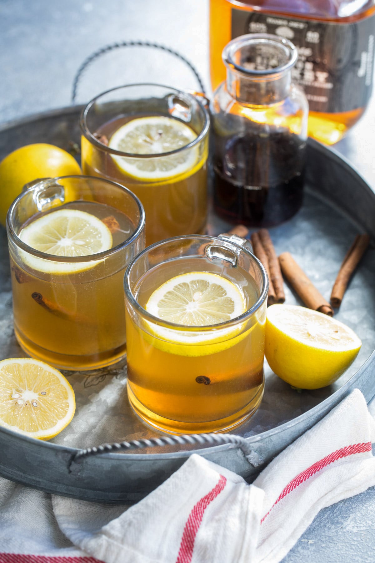 Hot toddies in clear glass mugs on a silver serving tray.