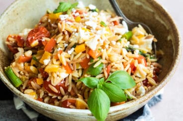 Orzo pasta salad in a bowl with a spoon.