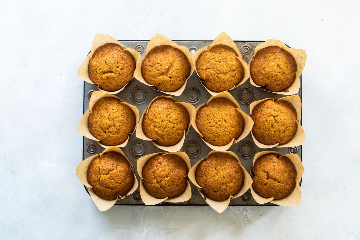 Twelve pumpkin muffins in a muffin tin.