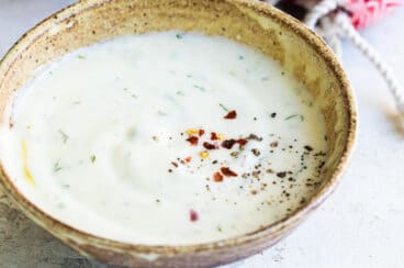 A small brown bowl filled with yogurt sauce.