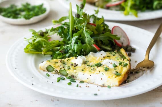 Asparagus frittata on a white plate with a salad.