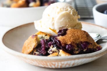 Two plates of blueberry cobbler with ice cream.