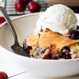 Two plates of cherry cobbler with ice cream.