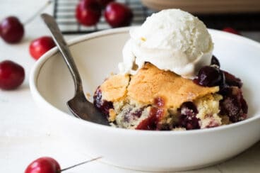 Two plates of cherry cobbler with ice cream.
