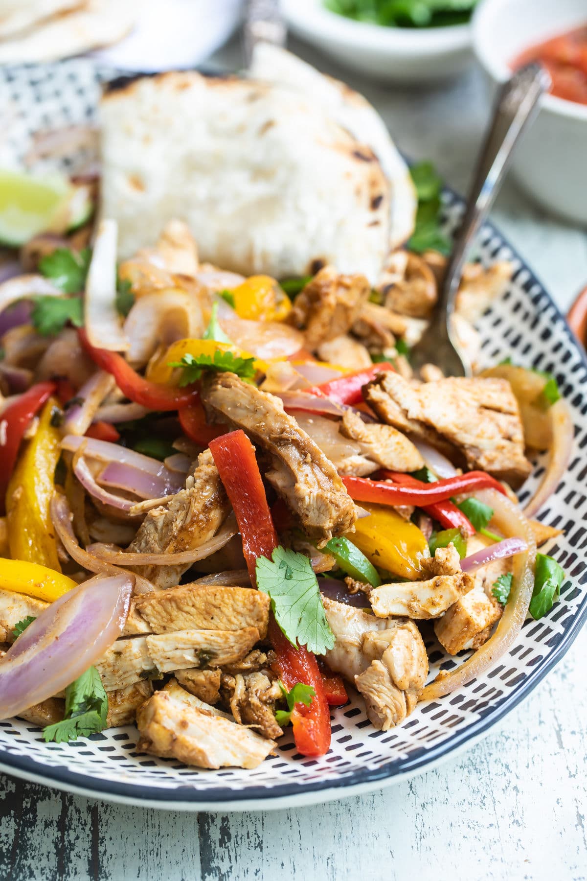 Chicken fajitas on a blue and white serving platter.