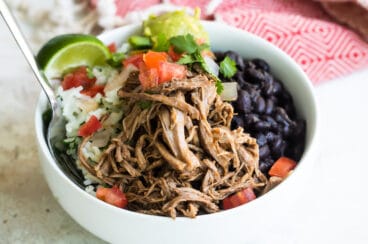 A bowl of Chipotle copycat Barbacoa beef with black beans, cilantro-lime rice, and pico de gallo salsa.