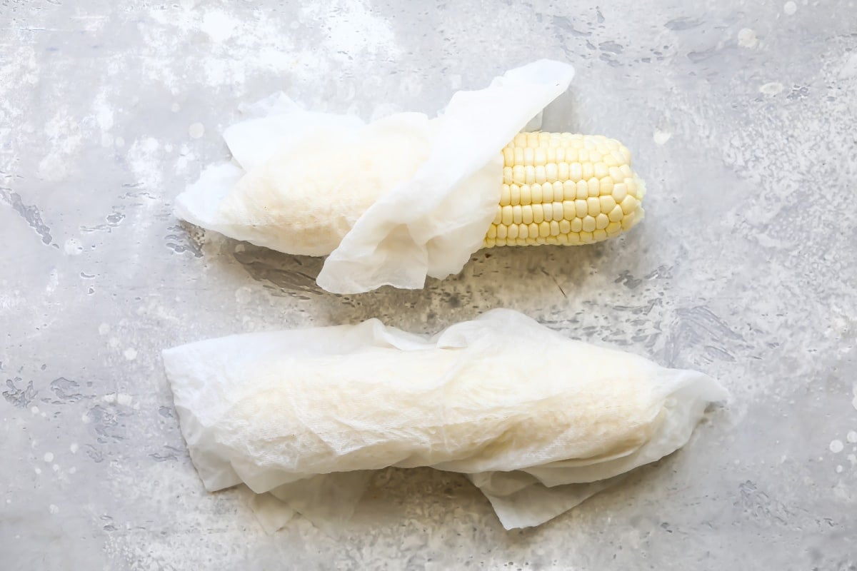 2 ears of corn wrapped in paper towel.